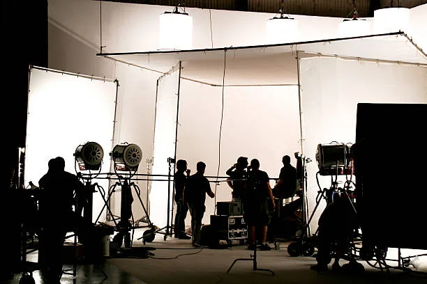 A film production crew operating camera and lighting equipment on set